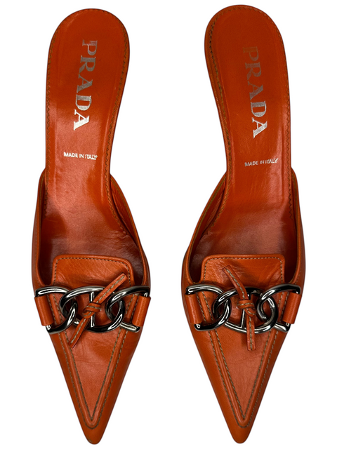 Mules Prada orange en cuir avec bout pointu et détail de chaîne argentée, proposées par CHEZ SNOW BUNNY.